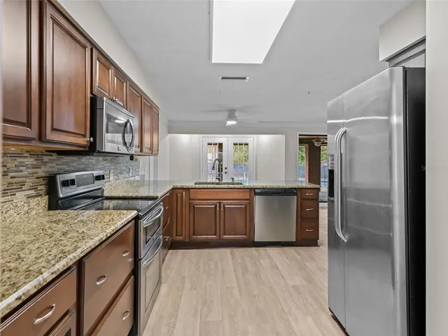 a kitchen with stainless steel appliances granite countertop a sink refrigerator and cabinets