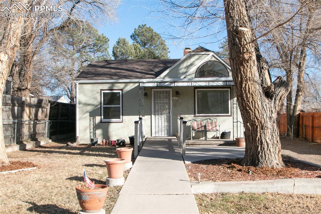 915 Alexander Road Colorado Springs, CO 80909 - Photo 1 of 24 a view of a white house with a large tree and yard