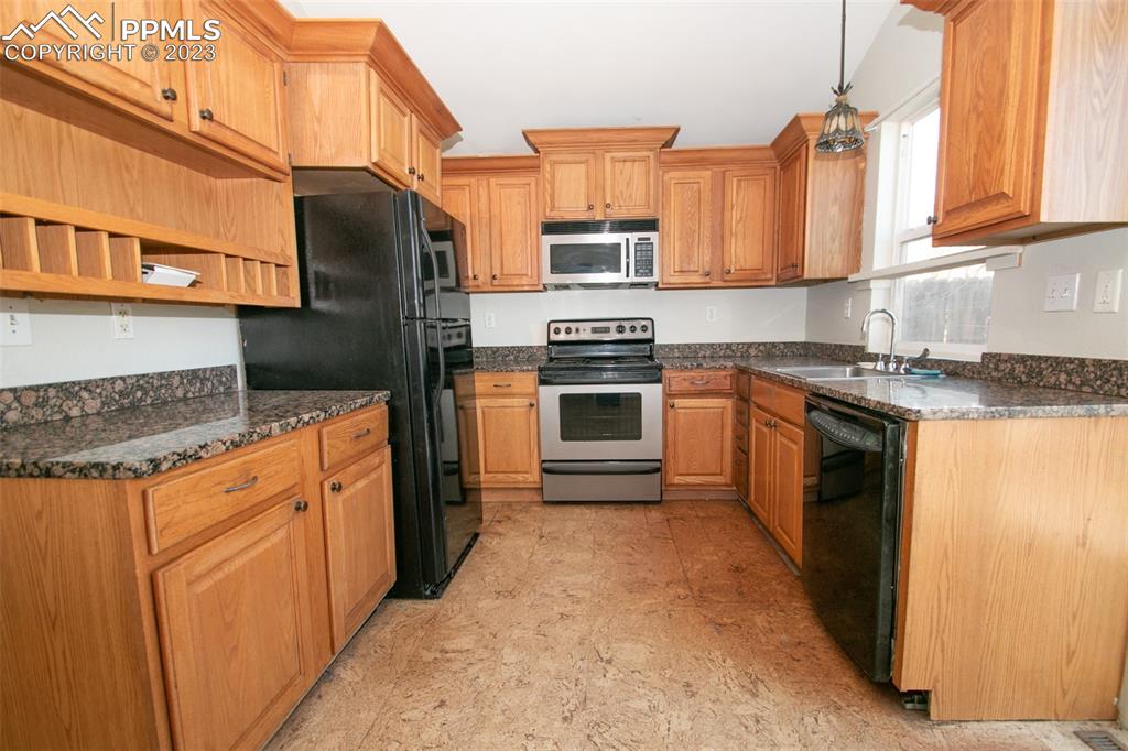 915 Alexander Road Colorado Springs, CO 80909 - Photo 18 of 24 a kitchen with stainless steel appliances granite countertop a stove a sink and a refrigerator