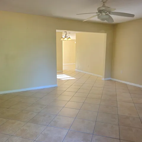 a view of an empty room with a chandelier fan
