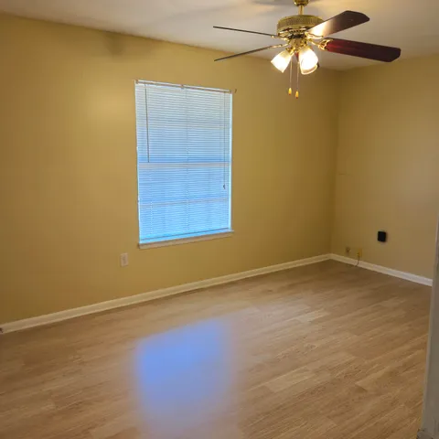 en empty room with windows and chandelier fan