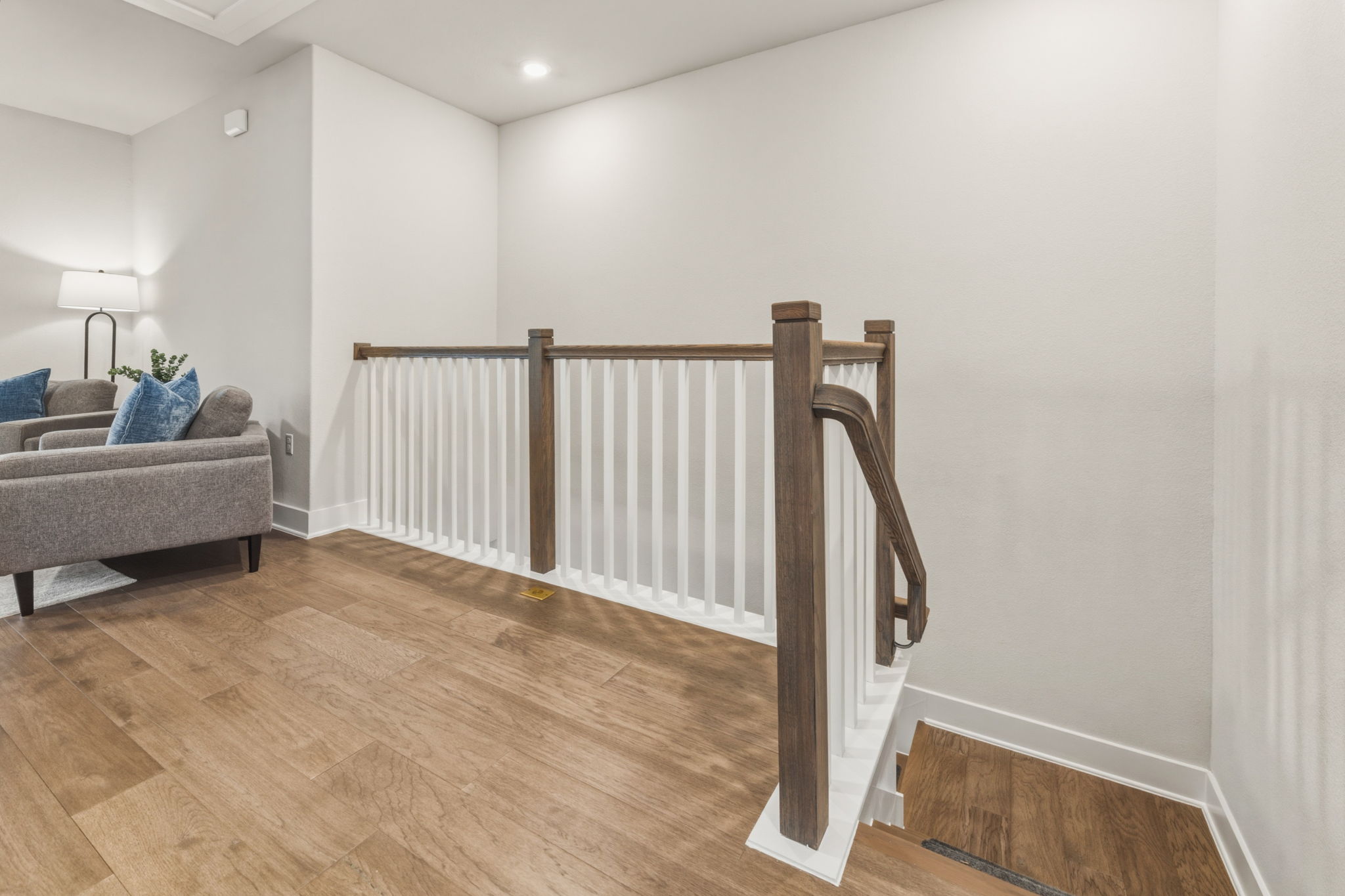 2929 Moreno Street Austin, TX 78723 - Photo 22 of 40 Hardwood flooring extending through a bright landing featuring a modern staircase with white balusters and a wood-finish handrail