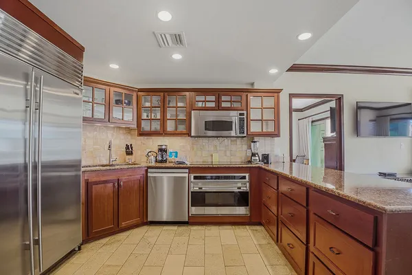 a large kitchen with stainless steel appliances granite countertop a refrigerator and a sink