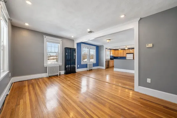 a view of empty room with wooden floor and fan