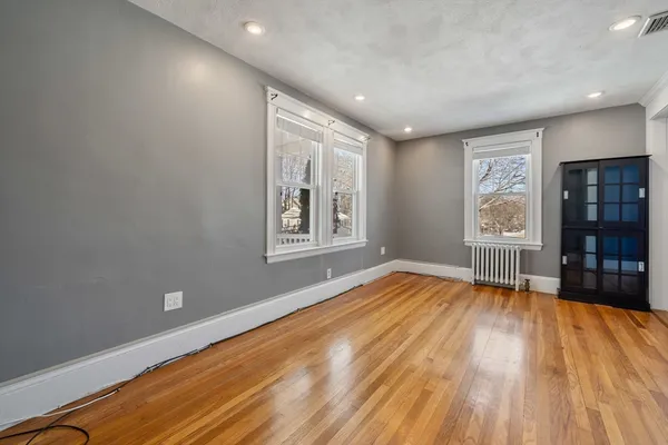 a view of an empty room with wooden floor and a window