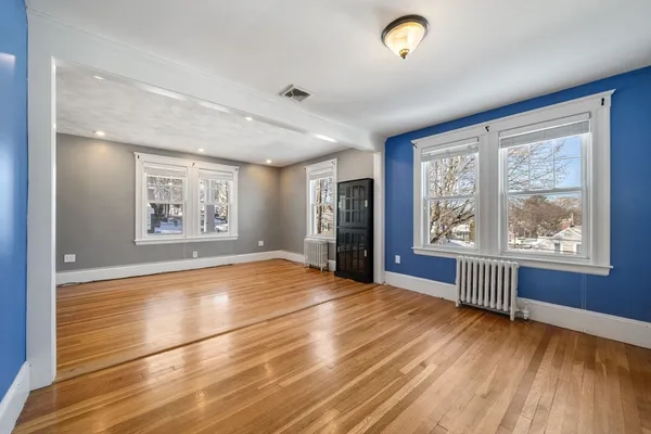 an empty room with wooden floor and windows
