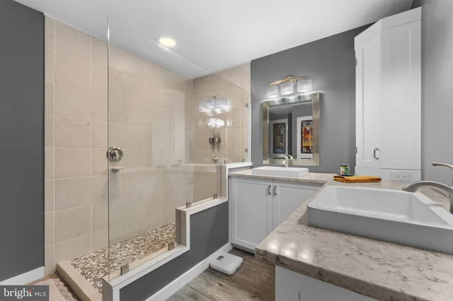 a spacious bathroom with a granite countertop sink a mirror and shower