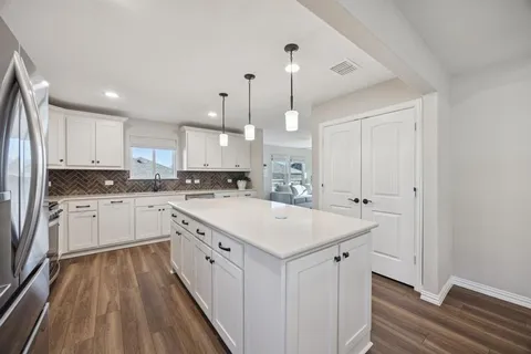 a kitchen with white cabinets appliances and sink