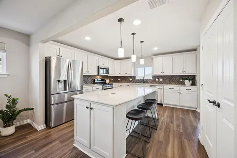 a kitchen with white cabinets stainless steel appliances and wooden floor