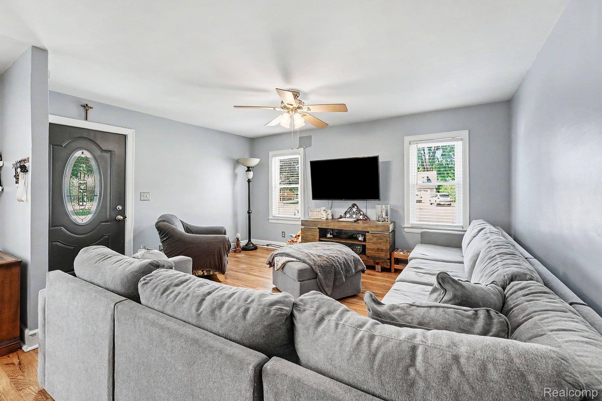 8215 Clinton River Road Sterling Heights, MI 48314 - Photo 8 of 28 Spacious living area featuring wood-finish flooring, light gray walls, a ceiling fan, and multiple windows