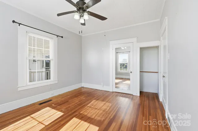 a view of empty room with wooden floor and fan