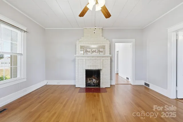 an empty room with windows fireplace and wooden floor