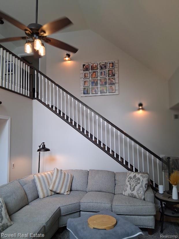 6807 Big Trail Road Holly, MI 48442 - Photo 16 of 45 Vaulted ceiling interior featuring a dark wood finish ceiling fan with Edison-style bulbs, a staircase with dark wood finish handrails and white balusters, and wall-mounted accent lighting