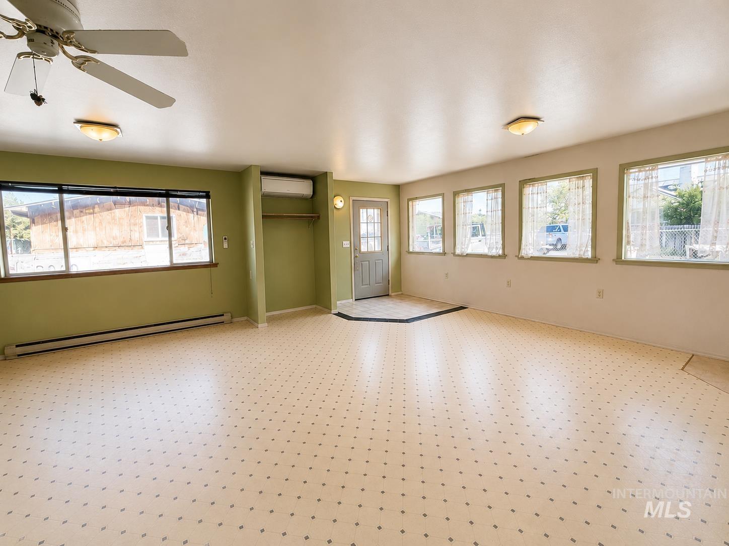 16434 Pride Lane Caldwell, ID 83607 - Photo 2 of 16 Spacious room featuring patterned flooring, multiple windows, a ceiling fan, baseboard heating, and a built-in air conditioning unit