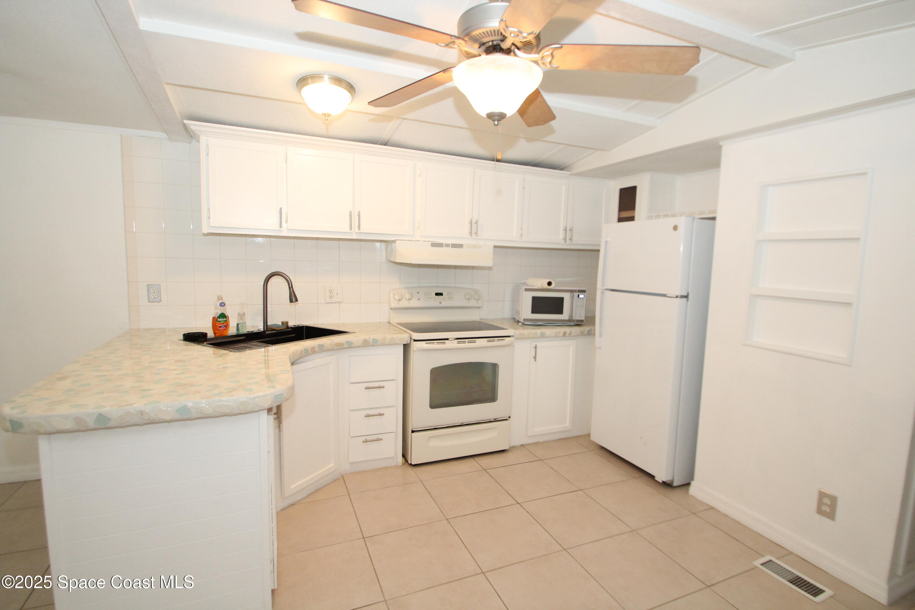 2132 Rocway Drive Melbourne, FL 32935 - Photo 3 of 8 a kitchen with white cabinets and white appliances