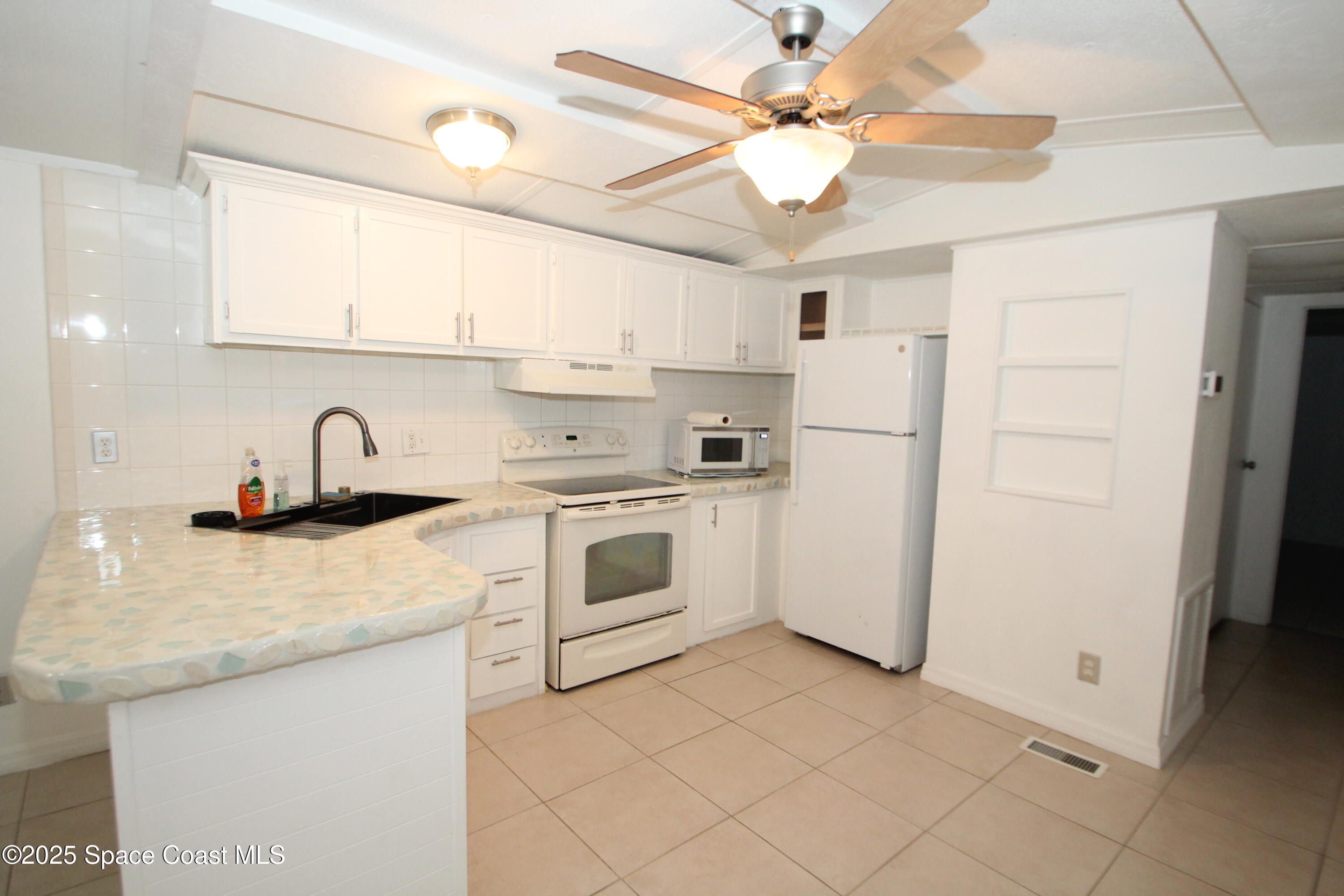 2132 Rocway Drive Melbourne, FL 32935 - Photo 4 of 8 a kitchen with white cabinets a sink appliances and a counter top space