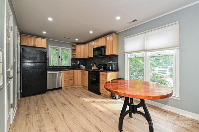 a kitchen with stainless steel appliances granite countertop a refrigerator a sink a stove a dining table and chairs