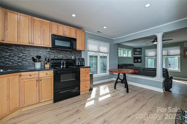 a living room with stainless steel appliances furniture a refrigerator and a stove top oven