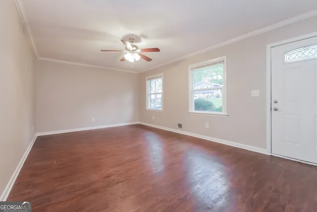 a view of empty room with wooden floor and fan