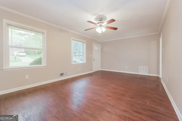 a view of empty room with wooden floor and fan