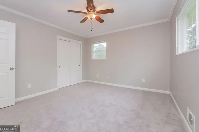 an empty room with windows and fan