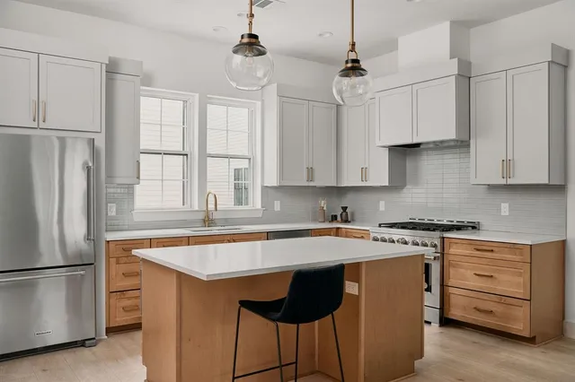 a kitchen with stainless steel appliances granite countertop a sink a stove a refrigerator and white cabinets