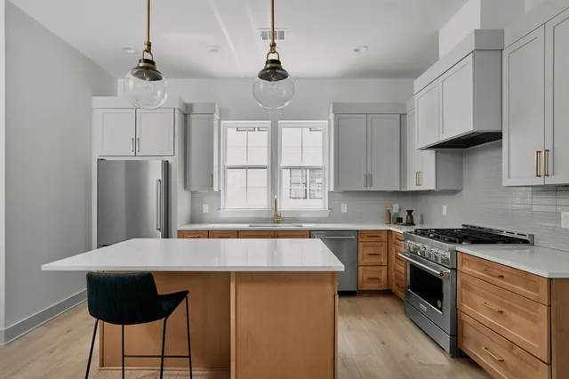 a kitchen with stainless steel appliances granite countertop a sink a stove a refrigerator and island with wooden floor