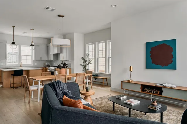 a living room with furniture kitchen view and a large window