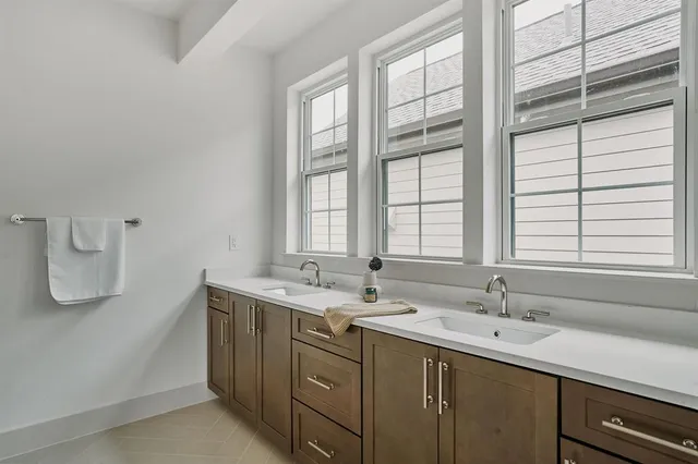 a bathroom with a double vanity sink a large mirror and a bathtub