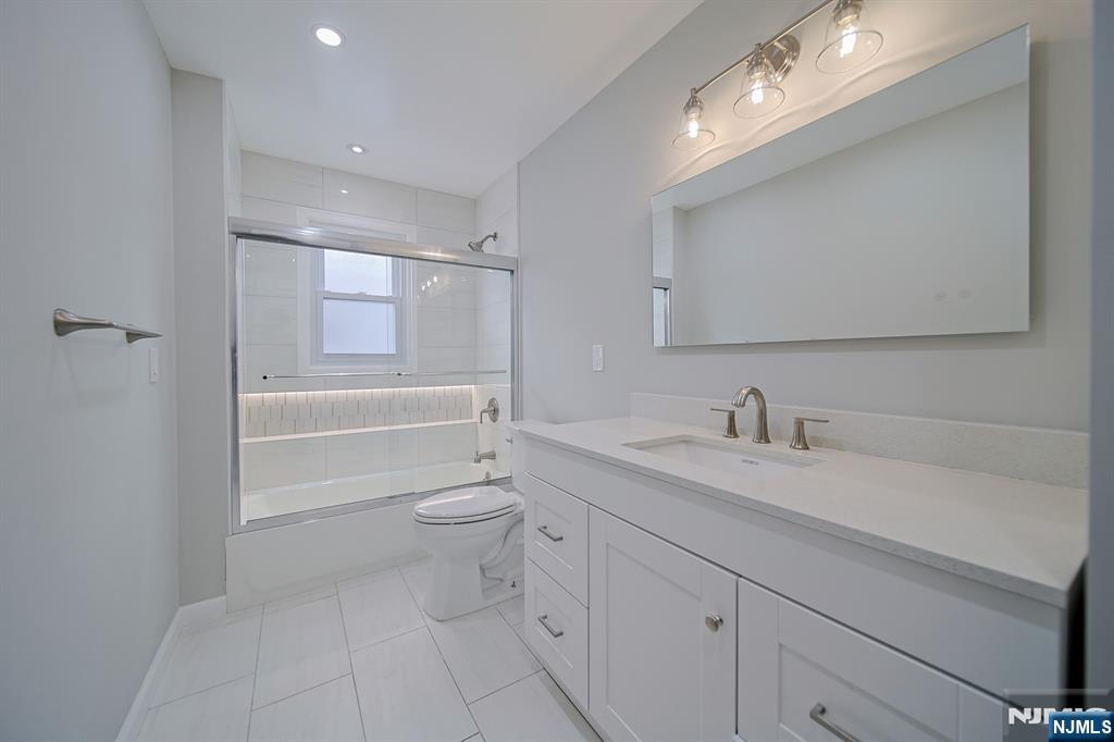 314 Garibaldi Avenue, Unit 1 Lodi, NJ 07644 - Photo 22 of 35 a bathroom with a granite countertop sink mirror vanity and toilet
