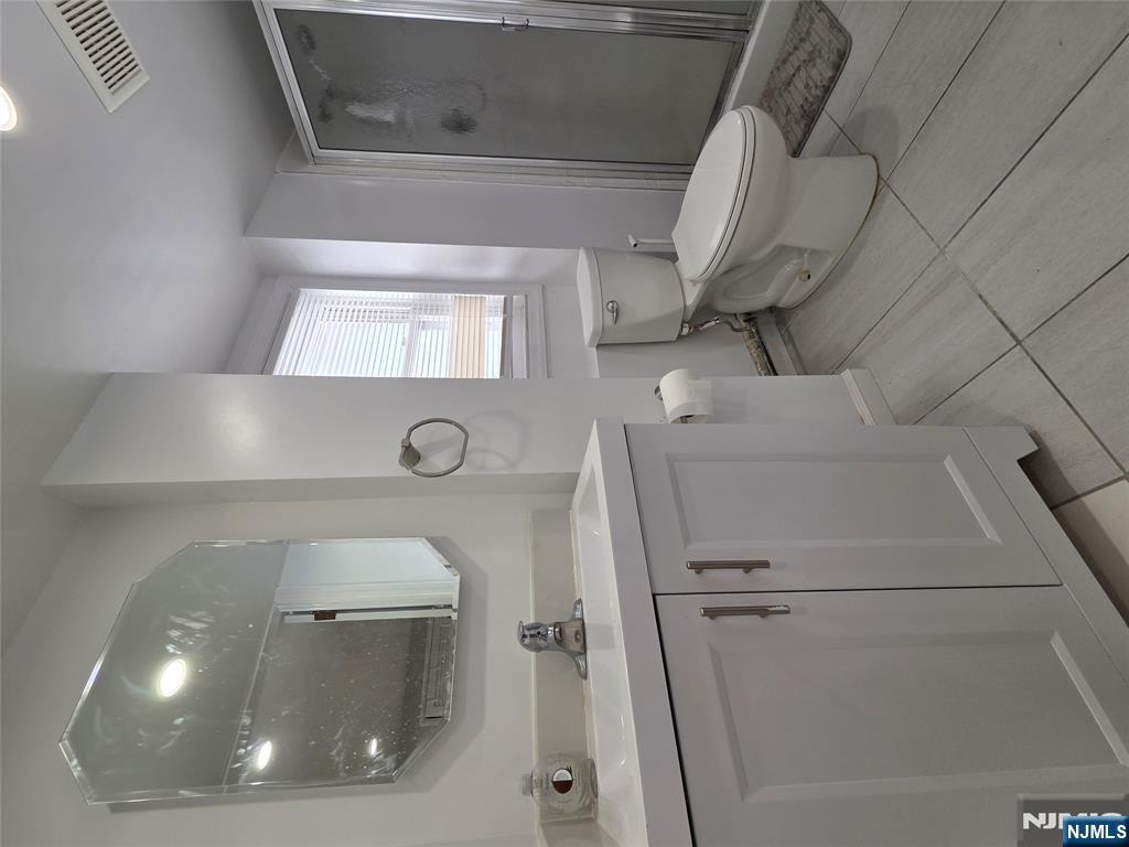 314 Garibaldi Avenue, Unit 1 Lodi, NJ 07644 - Photo 32 of 35 a bathroom with a toilet sink and mirror