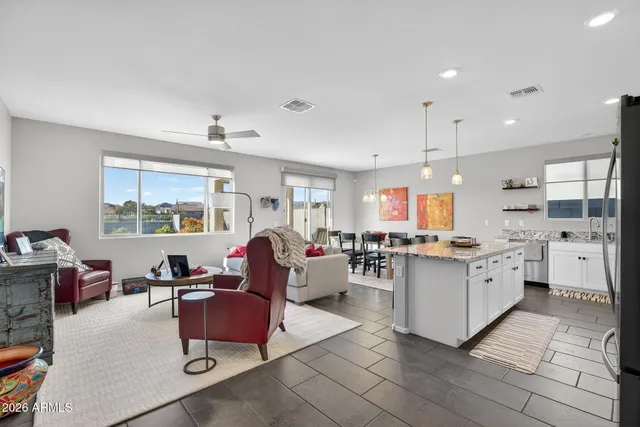 a large living room with stainless steel appliances kitchen island granite countertop a large window and a couch