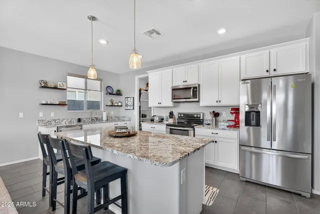 a kitchen with stainless steel appliances granite countertop a kitchen island hardwood floor sink stove and white cabinets
