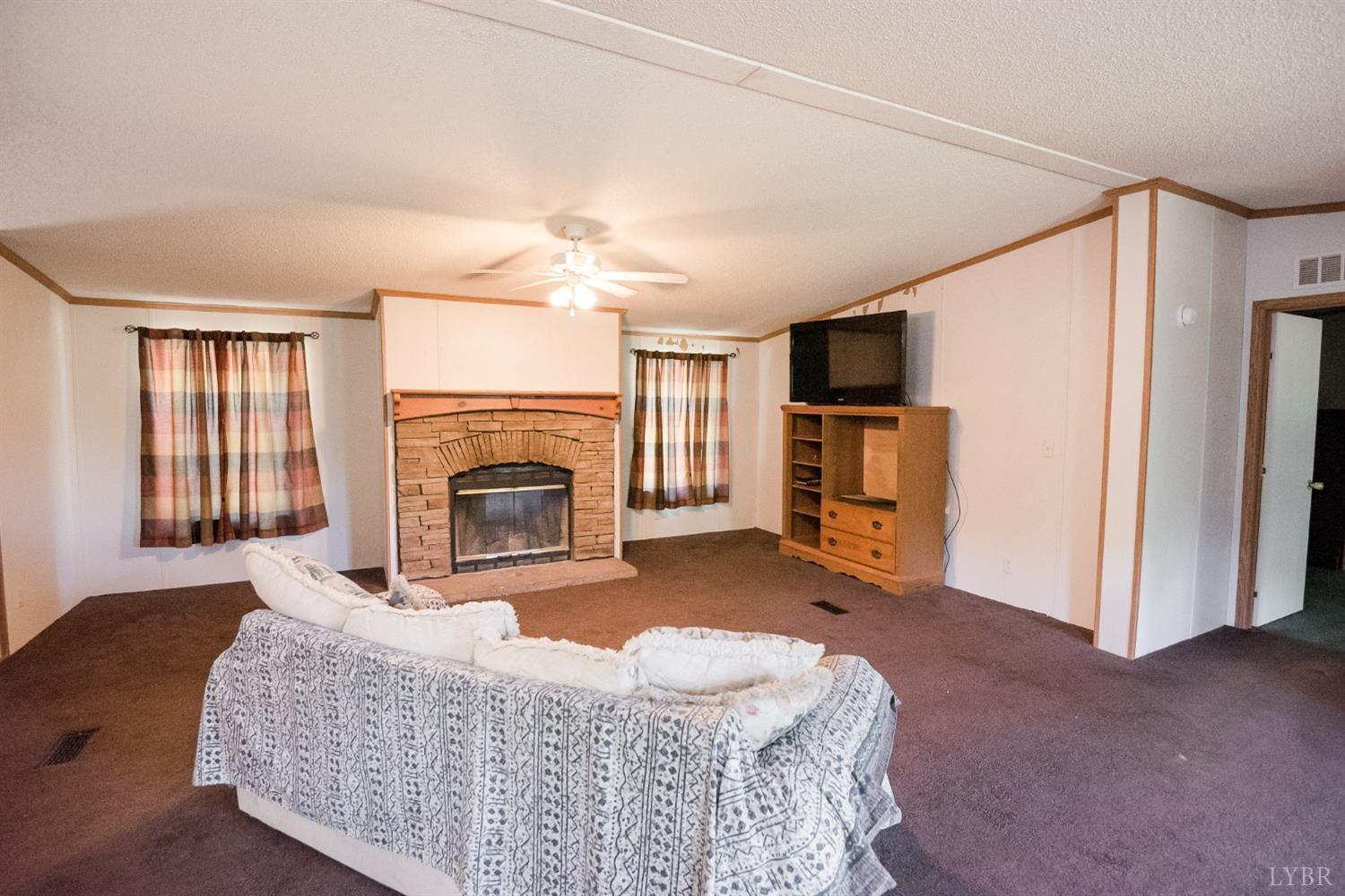 862 Snapps Mill Road Spout Spring, VA 24593 - Photo 7 of 29 a living room with furniture a flat screen tv and a fireplace