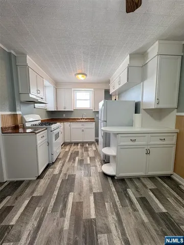 a kitchen with cabinets a sink and white appliances