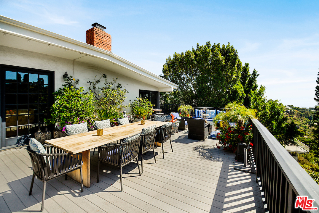 1077 Stradella Road Los Angeles, CA 90077 - Photo 23 of 25 a view of a patio with table and chairs with wooden floor and fence