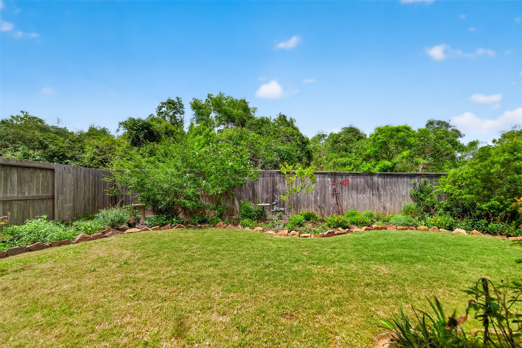 3415 Mckinney Ridge Drive Houston, TX 77059 - Photo 3 of 43 Private backyard has a well-manicured lawn, bordered by a wooden fence and lush greenery, offering a serene outdoor space.