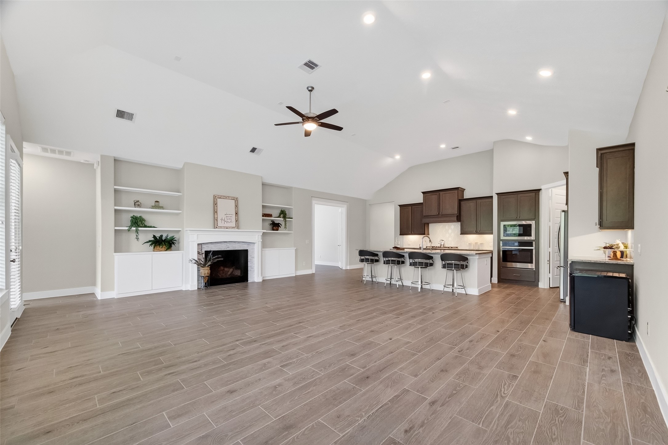 3415 Mckinney Ridge Drive Houston, TX 77059 - Photo 8 of 43 This photo showcases the spacious open-concept living area with vaulted ceiling, a cozy fireplace, built-in shelves, and wood-look tile flooring.