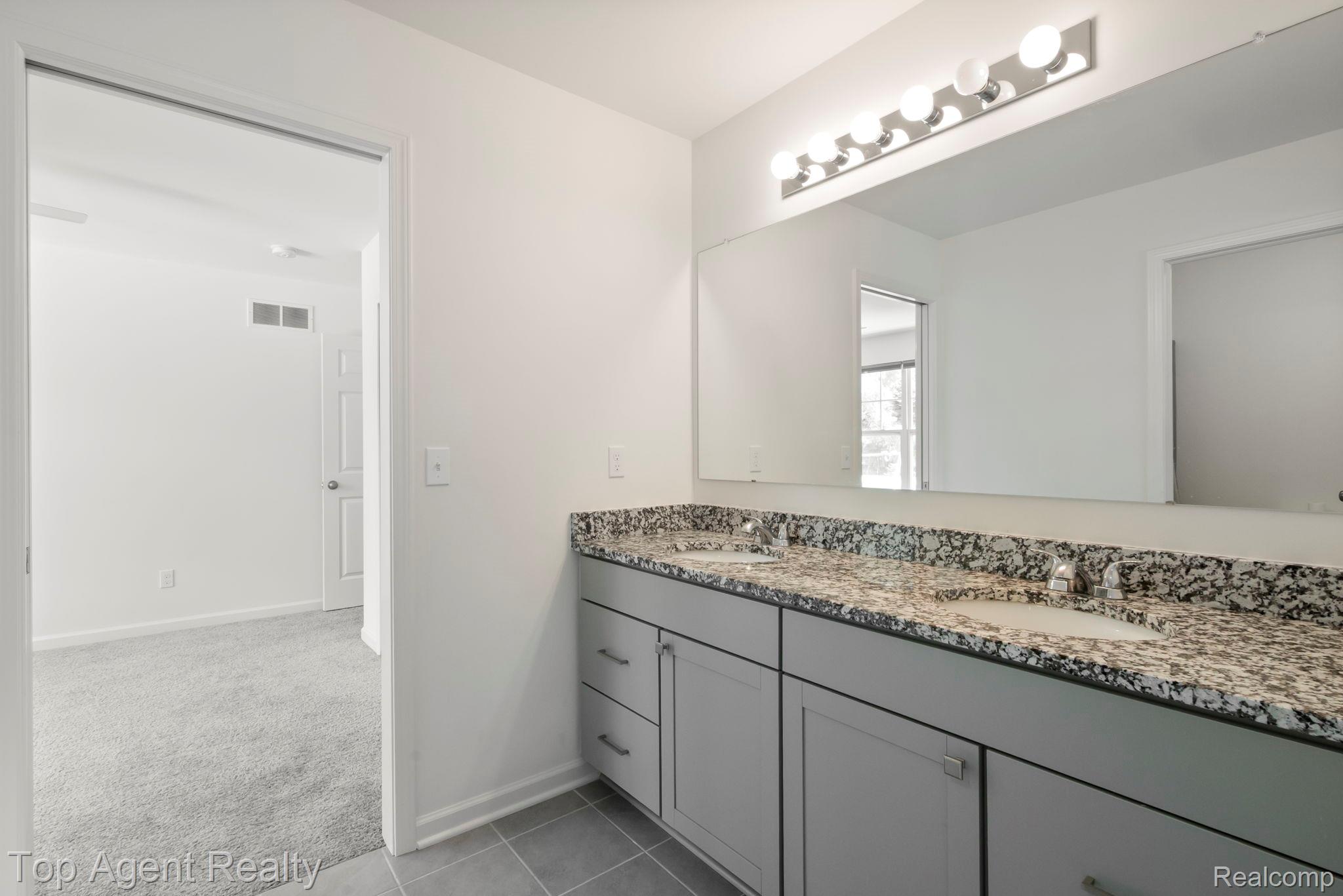 63770 Dequindre Road Washington, MI 48095 - Photo 36 of 61 Double vanity featuring a speckled countertop with undermount sinks, chrome faucets, and light gray cabinetry with brushed nickel hardware