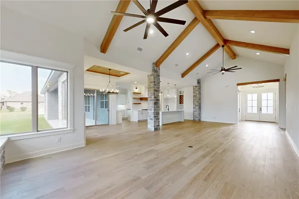 a kitchen with stainless steel appliances a sink dishwasher a stove a refrigerator and a dining table with wooden floor