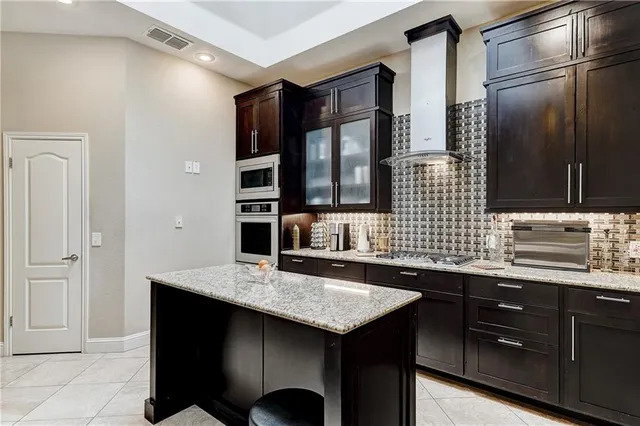 a kitchen with granite countertop a sink cabinets and stainless steel appliances