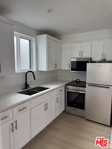 a kitchen with granite countertop white cabinets and white appliances