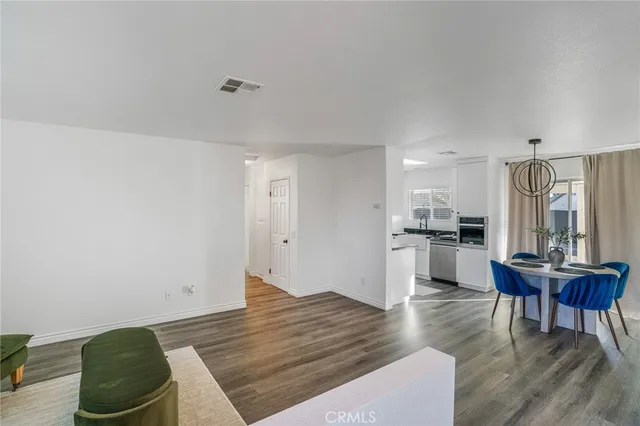 a living room with couches and kitchen view with wooden floor