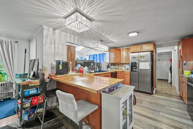 a room with stainless steel appliances lots of wooden furniture wooden floor and windows