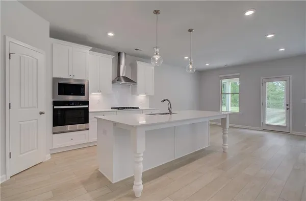 a large white kitchen with a sink a microwave a stove and refrigerator