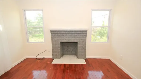 an empty room with wooden floor and a fireplace