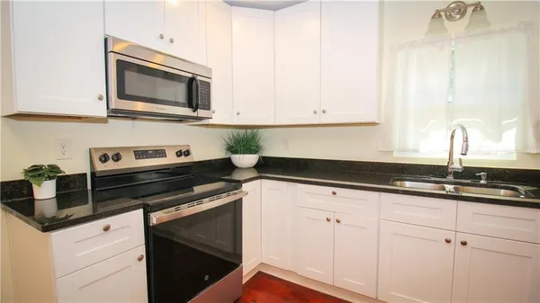 a kitchen with granite countertop white cabinets and black appliances