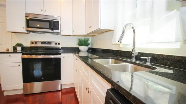 a kitchen with stainless steel appliances granite countertop a sink a stove and a microwave