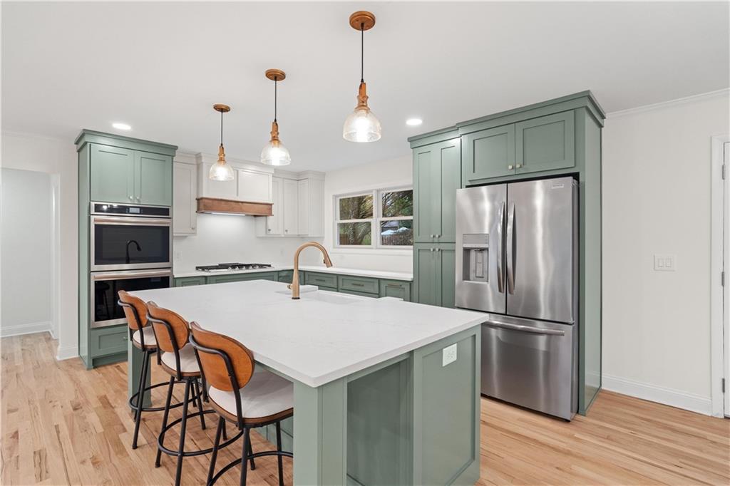 511 Boulevard Heights Calhoun, GA 30701 - Photo 15 of 69 a kitchen with stainless steel appliances a refrigerator a stove a kitchen island a dining table and chairs with wooden floor