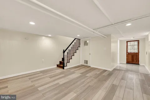 a view of an empty room with wooden floor and stairs